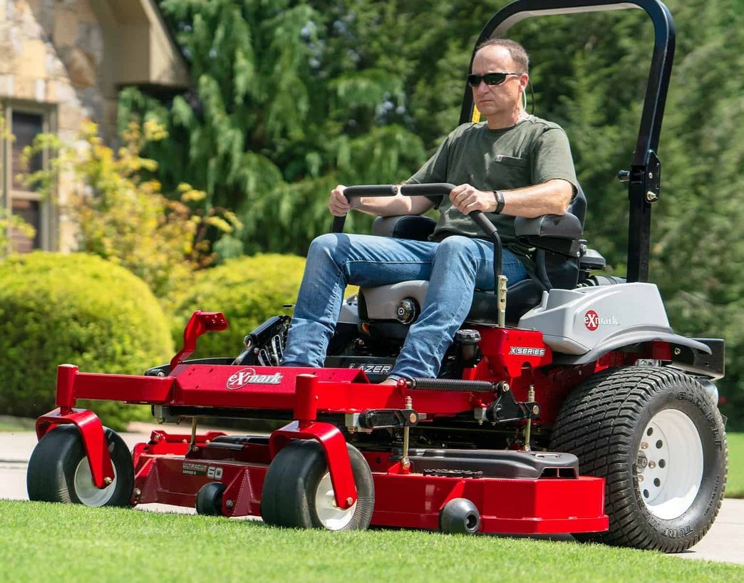 An expert operator on a high-performance Exmark zero-turn mower delivering a clean, uniform cut to a lush residential lawn.