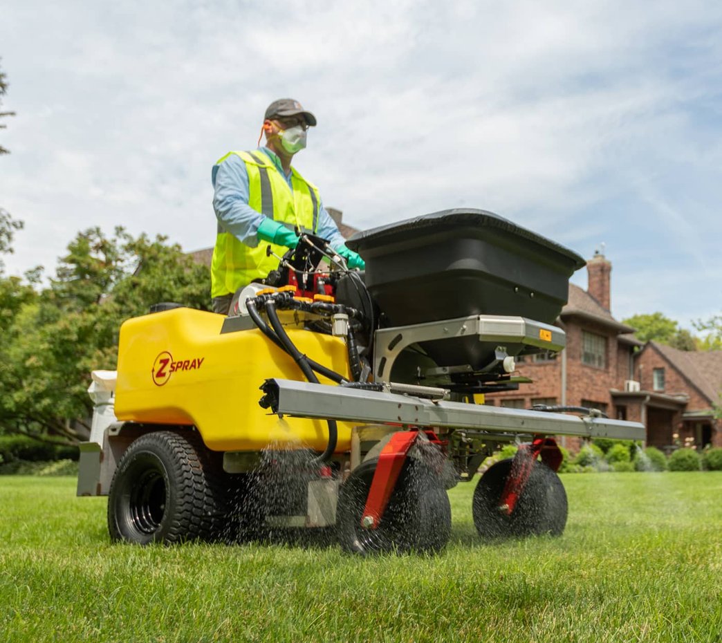 A professional using a Z-Spray machine to efficiently and evenly apply treatments to a lawn, ensuring a healthy and vibrant landscape.